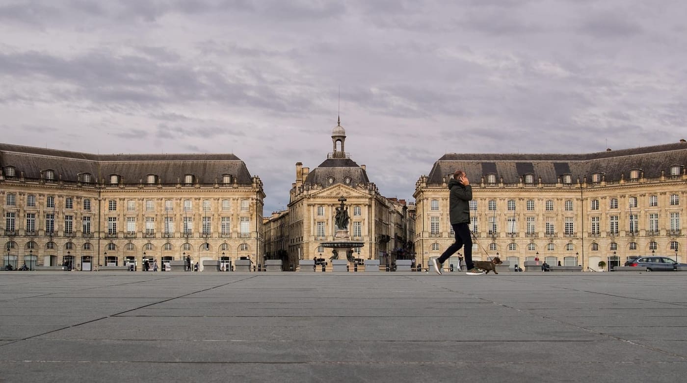 Iemand wandelt met een hond over een groot stadsplein
